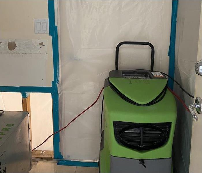 Dehumidifier sitting in front of a containment barrier for mold damage