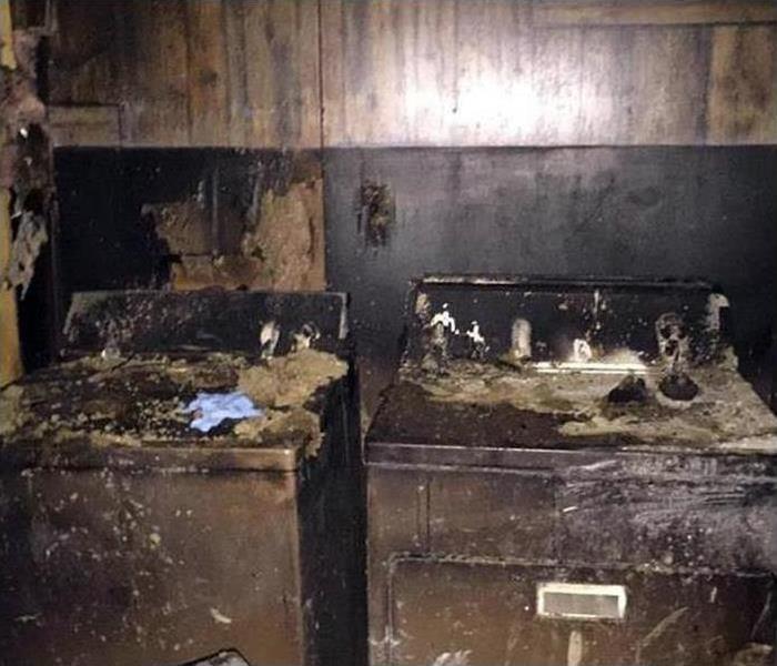 A washer and dryer covered in soot and smoke damage after a fire disaster