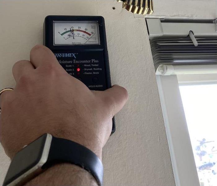 Technician holding a moisture meter on a water damaged wall