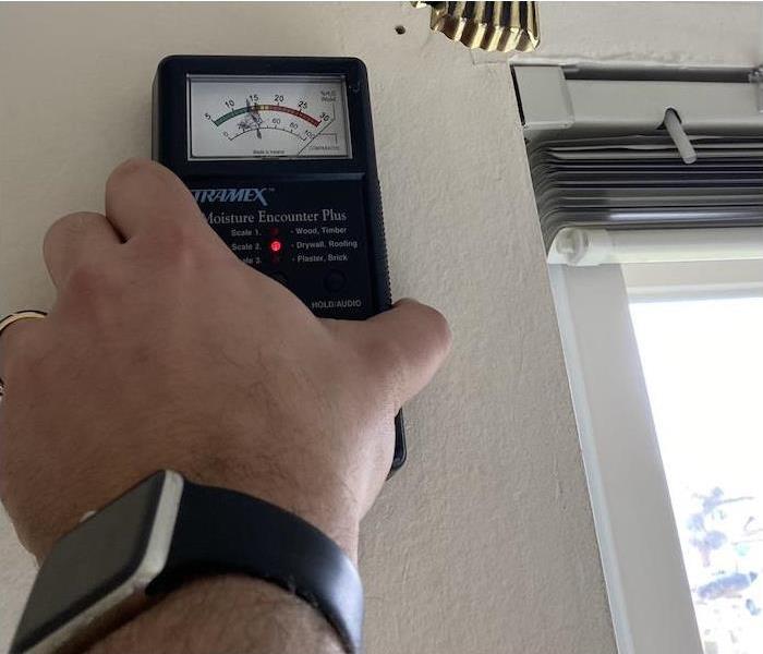 Technician holding a moisture meter on a water damaged wall